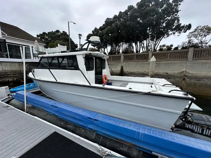 Slide: The Image of 1995 Almar 26 Sounder boat cruising in a marina with sailboats and palm trees. - 2