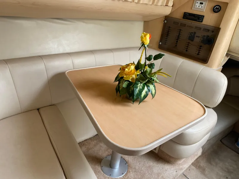 Slide: The Image of 1998 Regal 292 Commodore interior with beige seating and table, featuring a yellow flower arrangement. - 12
