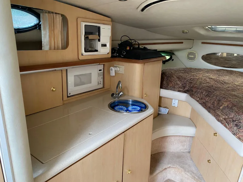 Slide: The Image of 1998 Regal 292 Commodore cabin with kitchenette, microwave, sink, and cozy sleeping area. - 16