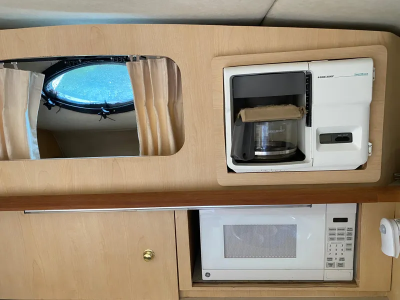 Slide: The Image of 1998 Regal 292 Commodore interior with coffee maker, microwave, and porthole window. - 18