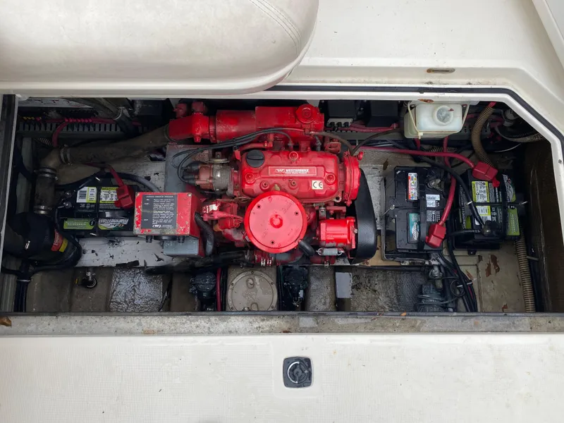 Slide: The Image of Engine compartment of a 1998 Regal 292 Commodore boat, featuring a red engine and batteries. - 28