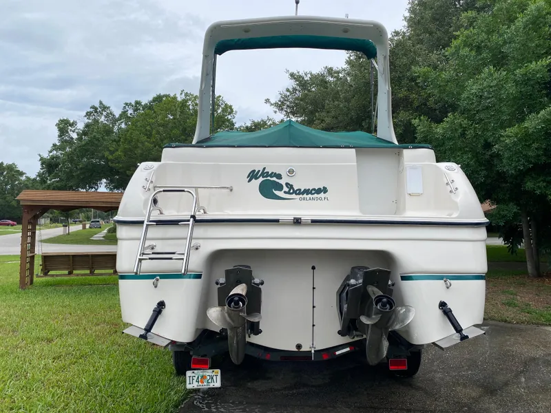Slide: The Image of 1998 Regal 292 Commodore boat, rear view, parked on grass with trees in background. - 7