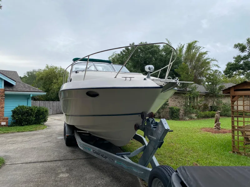 Slide: The Image of 1998 Regal 292 Commodore boat on trailer in driveway, surrounded by greenery. - 9