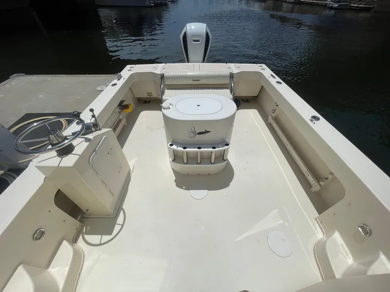 Slide: The Image of 2008 Parker 2520 XL Sport Cabin boat deck with seating and storage, docked by the water. - 10