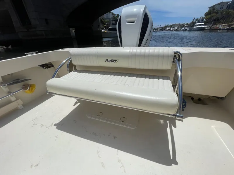 Slide: The Image of 2008 Parker 2520 XL Sport Cabin boat with cushioned seating, docked near a bridge. - 14