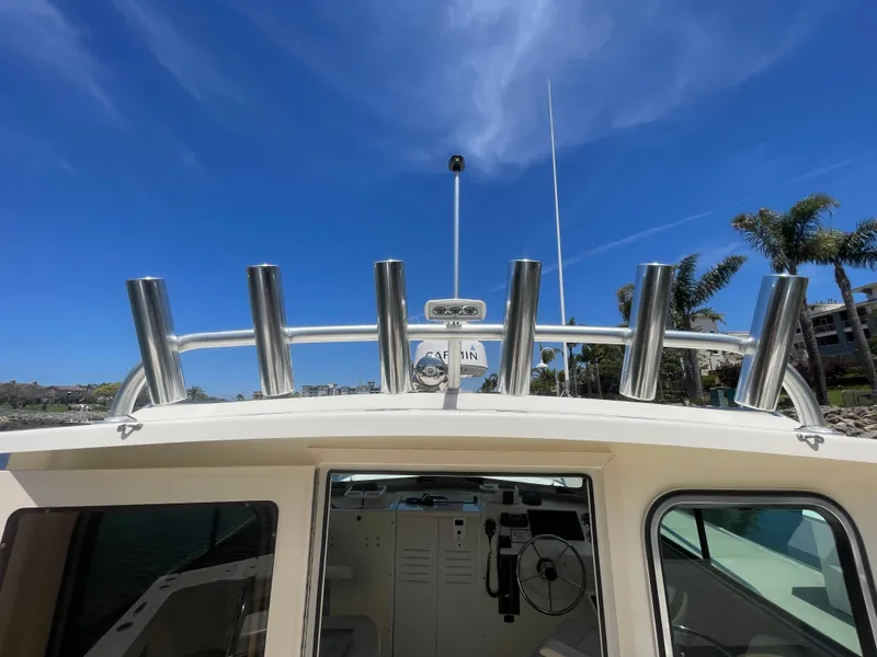 Slide: The Image of 2008 Parker 2520 XL Sport Cabin boat with rod holders, under a clear blue sky. - 16