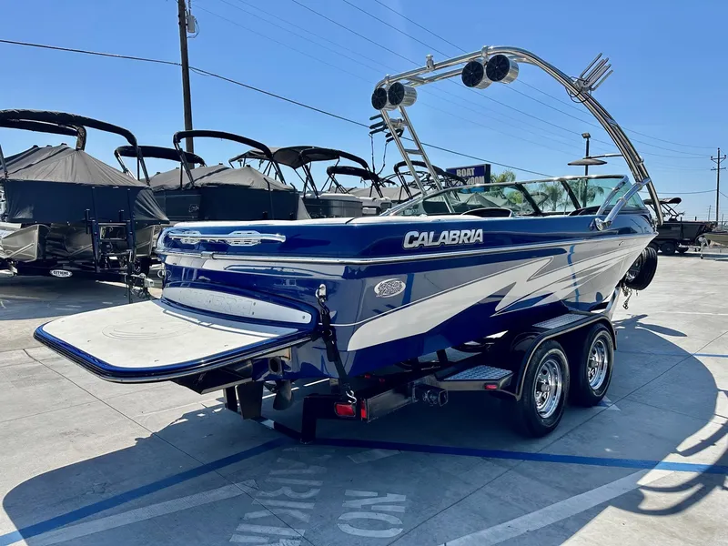 Slide: The Image of 2006 Calabria Boats Wakeboard Boat Cal-Air Pro-V, blue and white, parked on a trailer. - 5