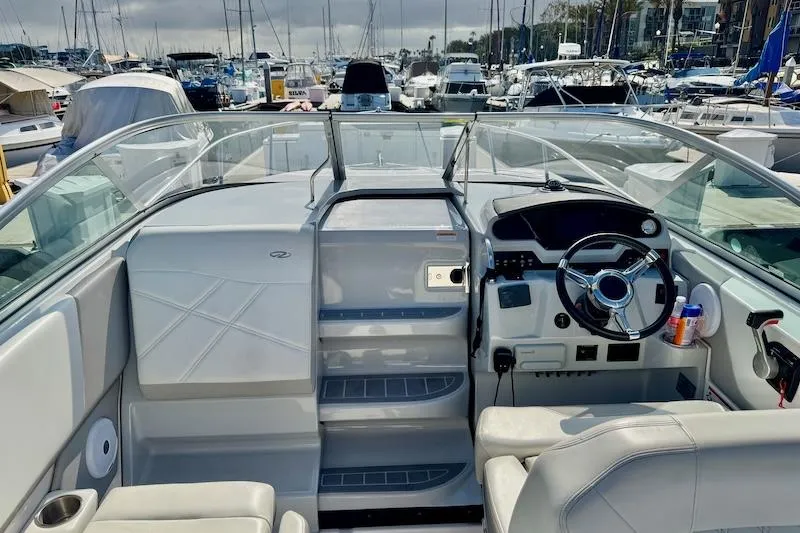 Slide: The Image of 2020 Regal 26 XO boat interior with helm, seating, and marina background. - 11
