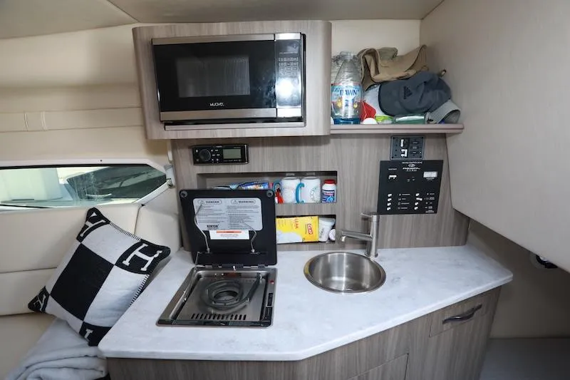 Slide: The Image of Compact kitchen area in a 2020 Regal 26 XO boat with microwave, stove, and sink. - 33