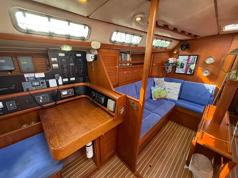 Slide: The Image of 1997 Westerly Oceanlord yacht interior with wooden finish, blue seating, and navigation station. - 31