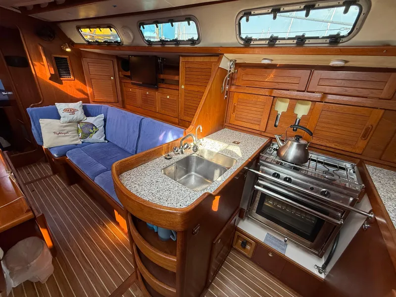 Slide: The Image of Interior of 1997 Westerly Oceanlord yacht with kitchen, blue sofa, and wooden cabinetry. - 32