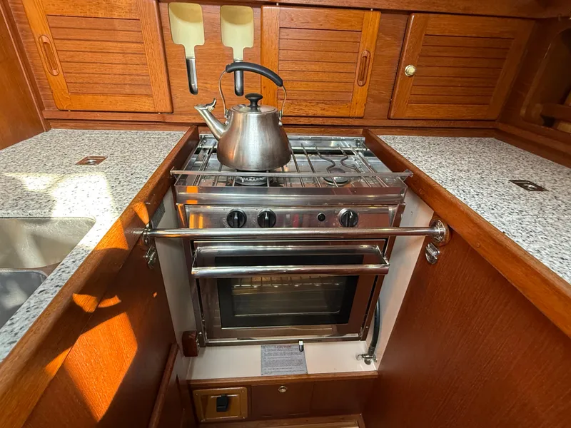 Slide: The Image of 1997 Westerly Oceanlord yacht kitchen with stove, kettle, and wooden cabinetry. - 34
