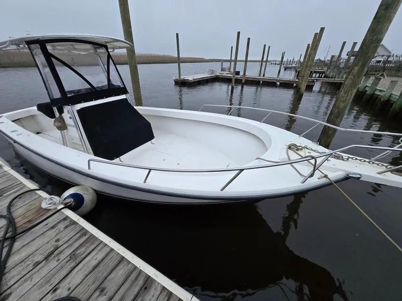 Slide: The Image of 1999 Shamrock 220 Open boat docked at a marina, featuring a sleek white design. - 11