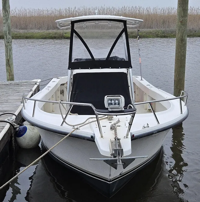 Slide: The Image of 1999 Shamrock 220 Open boat docked by the water, featuring a sleek design and canopy. - 13