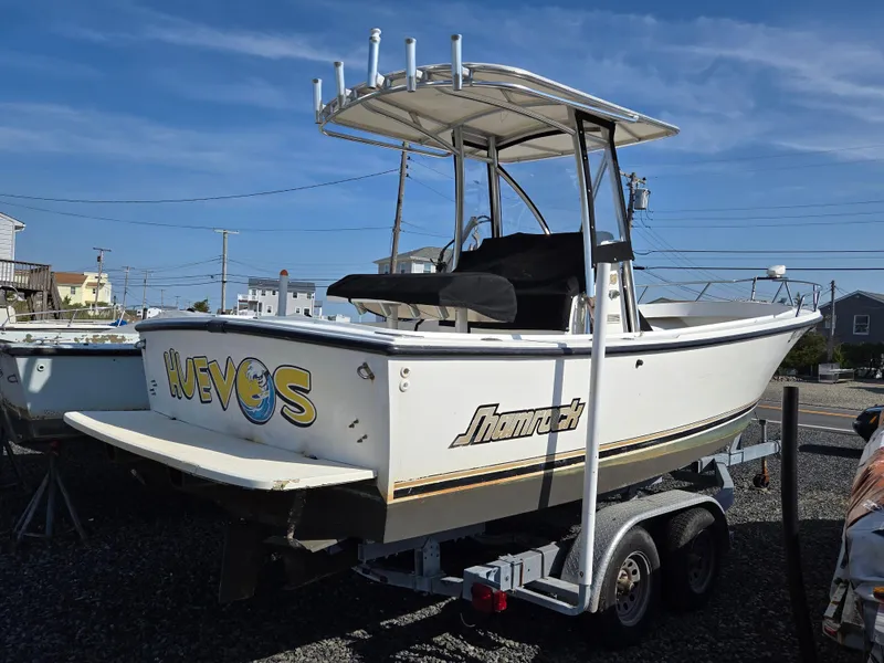 Slide: The Image of 1999 Shamrock 220 Open boat on trailer, featuring T-top and custom graphics. - 16