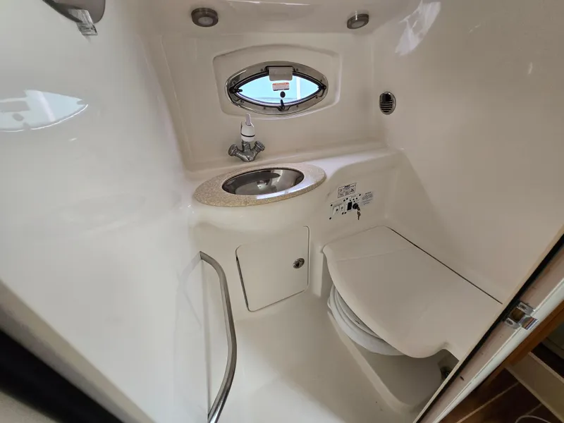 Slide: The Image of 2008 Chaparral 290 Signature boat bathroom with sink, toilet, and porthole window. - 4