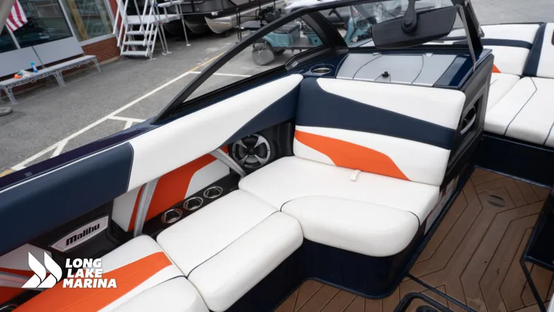 Slide: The Image of 2019 Malibu MXZ boat interior with white, orange, and navy seating at Long Lake Marina. - 18