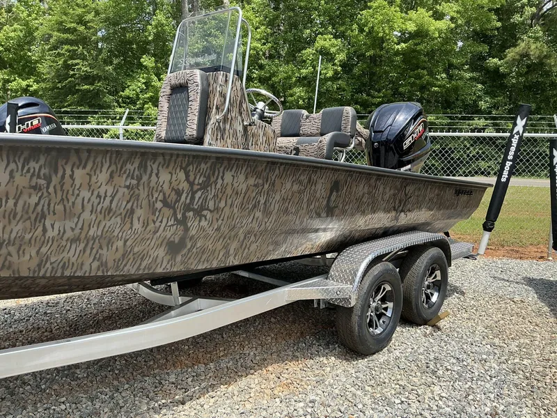 Slide: The Image of 2025 Xpress Hyper-Lift Series H22B boat on trailer, camo design, parked outdoors. - 3