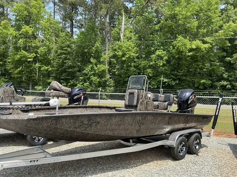 Slide: The Image of 2025 Xpress Hyper-Lift Series H22B boat on trailer, camo design, parked outdoors. - 1