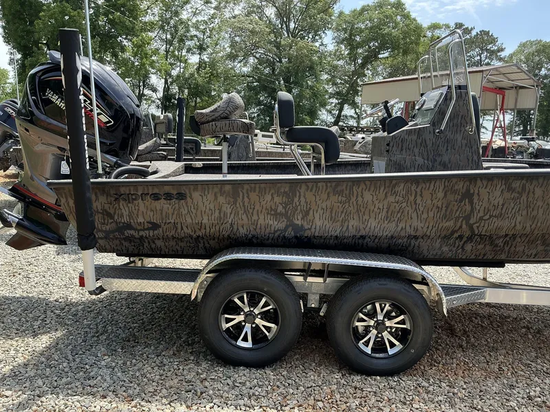 Slide: The Image of 2025 Xpress Hyper-Lift Series H22B boat on trailer, camo design, parked outdoors. - 12