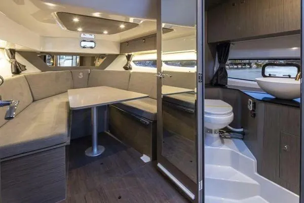 Slide: The Image of 2023 Beneteau GT32 interior with dining area and compact bathroom, featuring modern design and lighting. - 16
