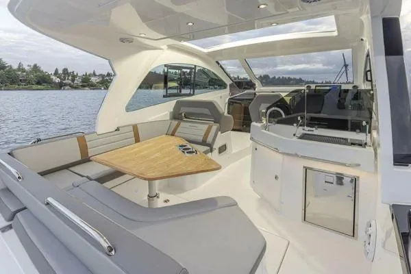Slide: The Image of 2023 Beneteau GT32 yacht interior with seating, table, and helm, on a serene water backdrop. - 9