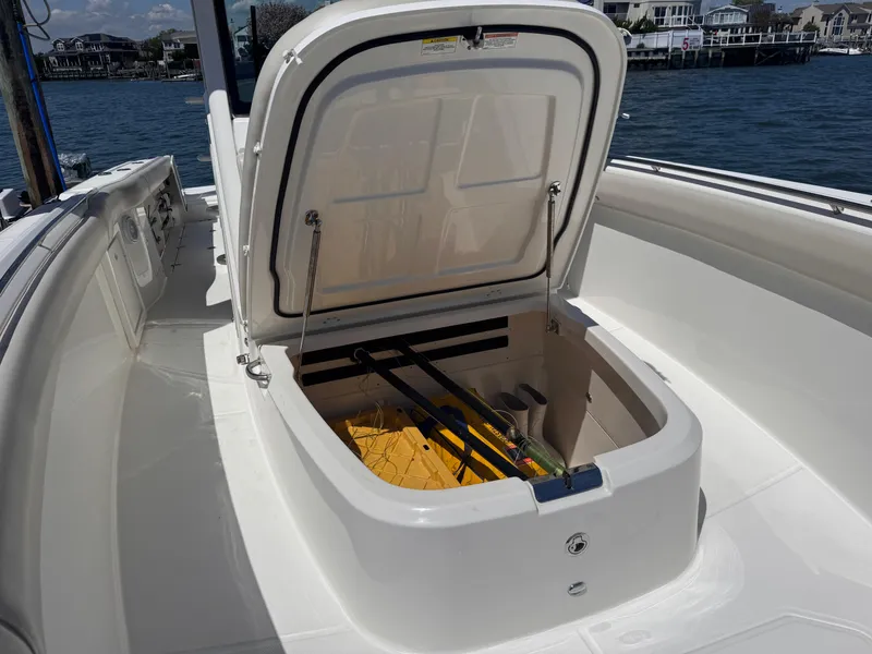 Slide: The Image of Open storage compartment on 2018 Boston Whaler 330 Outrage boat, docked by waterfront homes. - 19