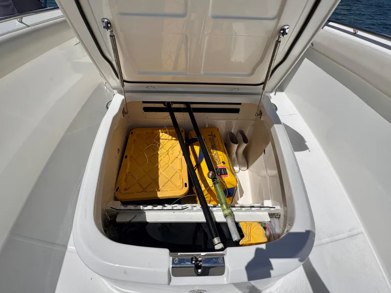 Slide: The Image of Open storage compartment on 2018 Boston Whaler 330 Outrage boat, containing fishing gear and supplies. - 20