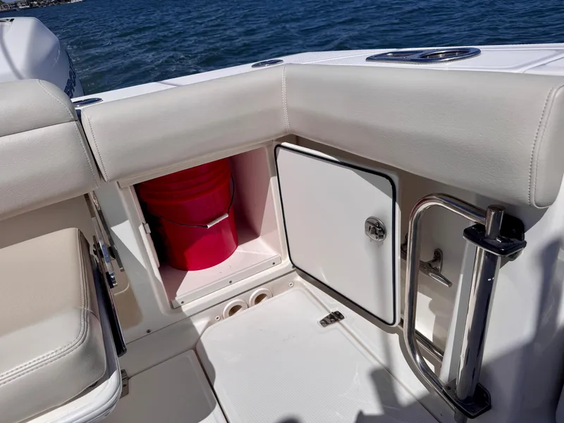 Slide: The Image of 2018 Boston Whaler 330 Outrage boat interior with storage compartment and red bucket. - 30