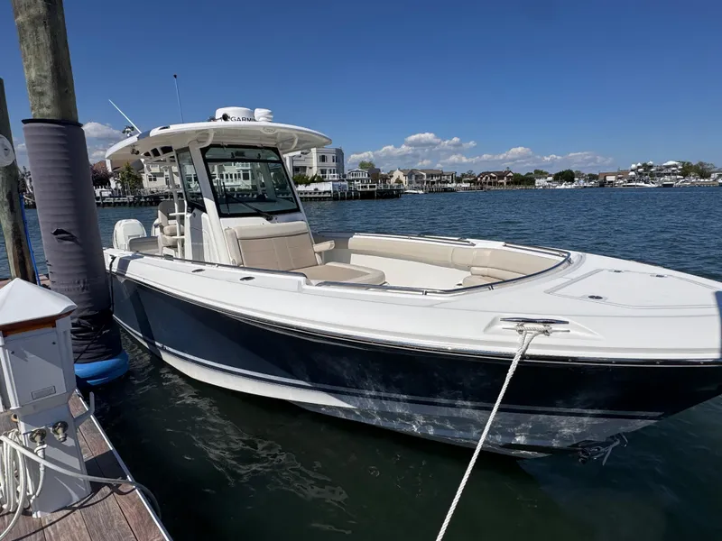Slide: The Image of 2018 Boston Whaler 330 Outrage docked by waterfront homes under clear blue sky. - 45