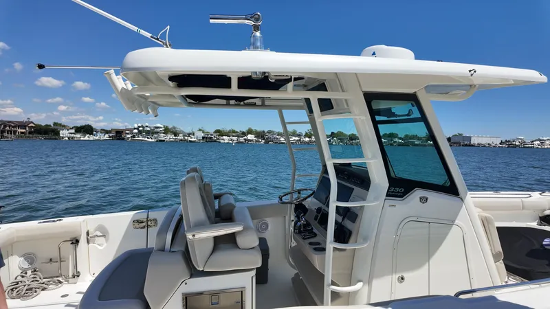 Slide: The Image of 2018 Boston Whaler 330 Outrage boat on water, featuring helm and seating area. - 5