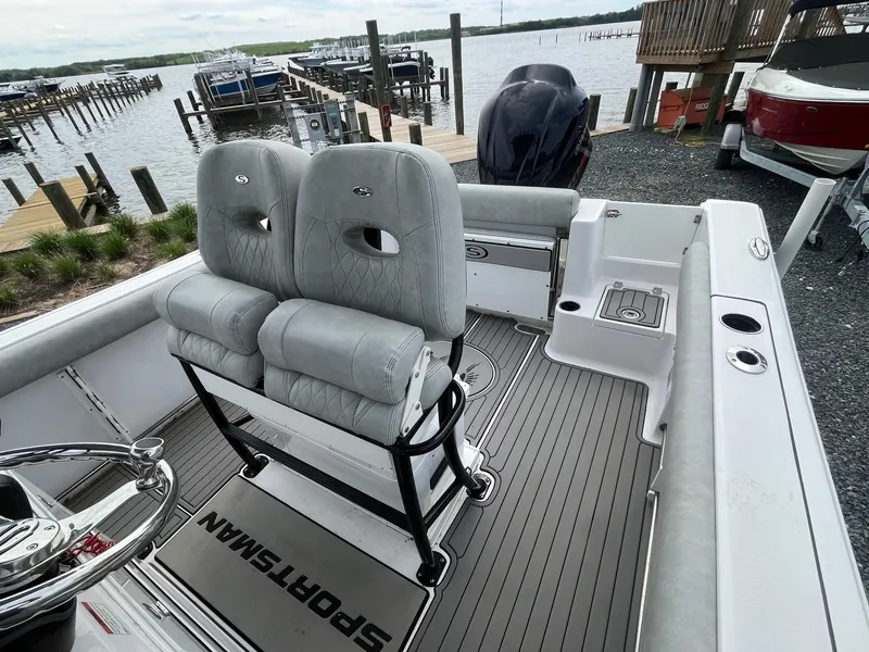 Slide: The Image of 2020 Sportsman Open 232 Center Console boat interior with dual seats, docked by the water. - 13