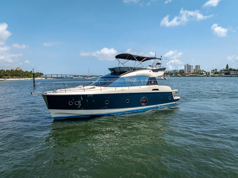Slide: The Image of 2015 Beneteau Monte Carlo 5 yacht cruising on a sunny day, coastal cityscape in background. - 1