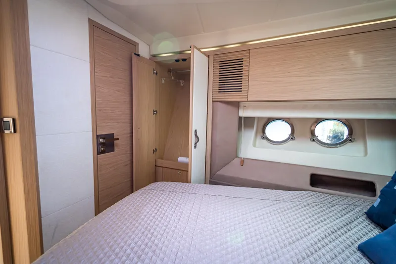 Slide: The Image of 2015 Beneteau Monte Carlo 5 cabin interior with bed, portholes, and wooden cabinetry. - 42