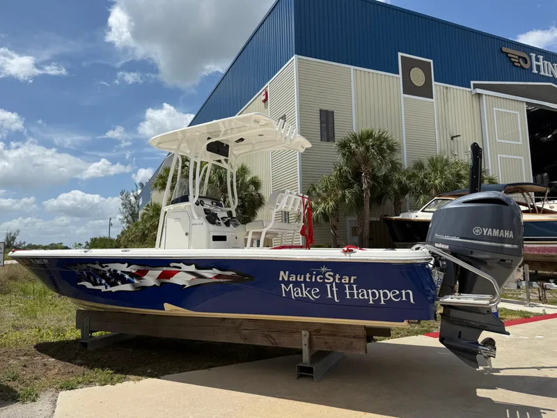 The Image of 2015 NauticStar 244 XTS boat with Yamaha engine, parked near a warehouse under a blue sky. - 0