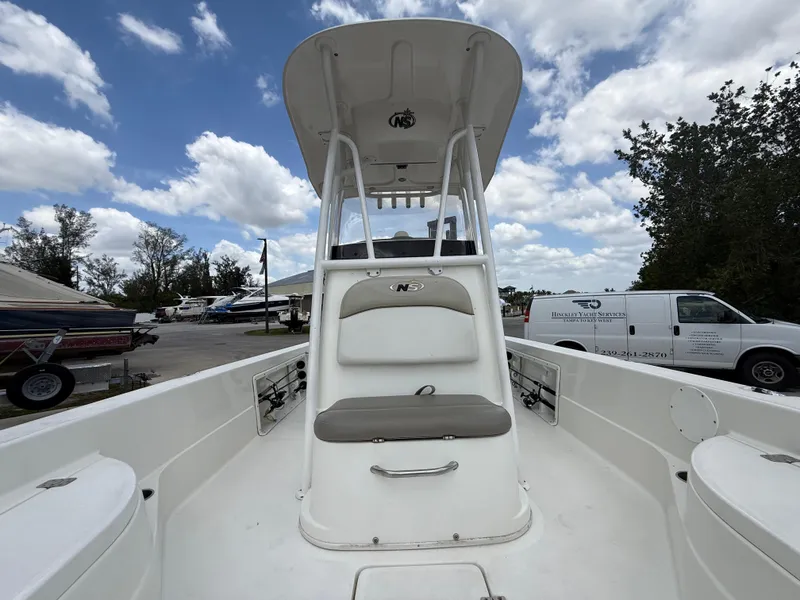 Slide: The Image of 2015 NauticStar 244 XTS boat with T-top, parked outdoors under a cloudy sky. - 13
