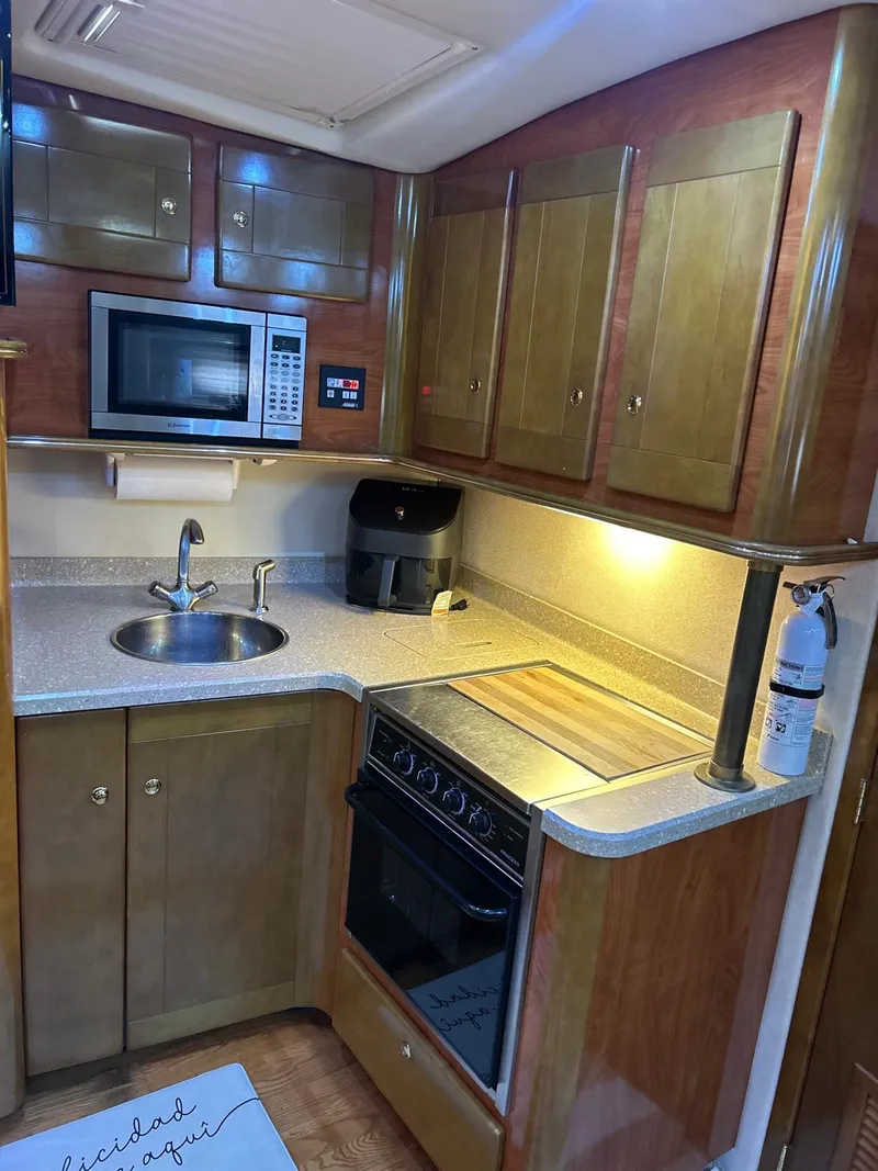 Slide: The Image of 2005 Rinker Fiesta Vee 410 yacht kitchen with microwave, stove, and sink. - 23