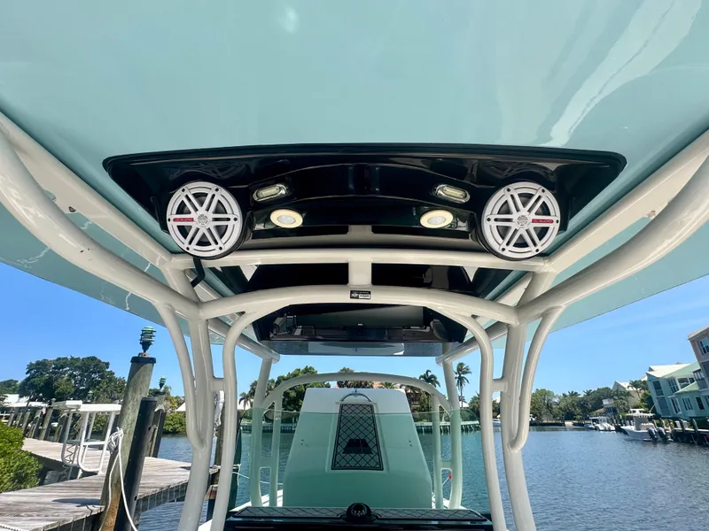 Slide: The Image of 2019 Wellcraft 262 Fisherman boat with speakers and canopy, docked by a scenic waterfront. - 17