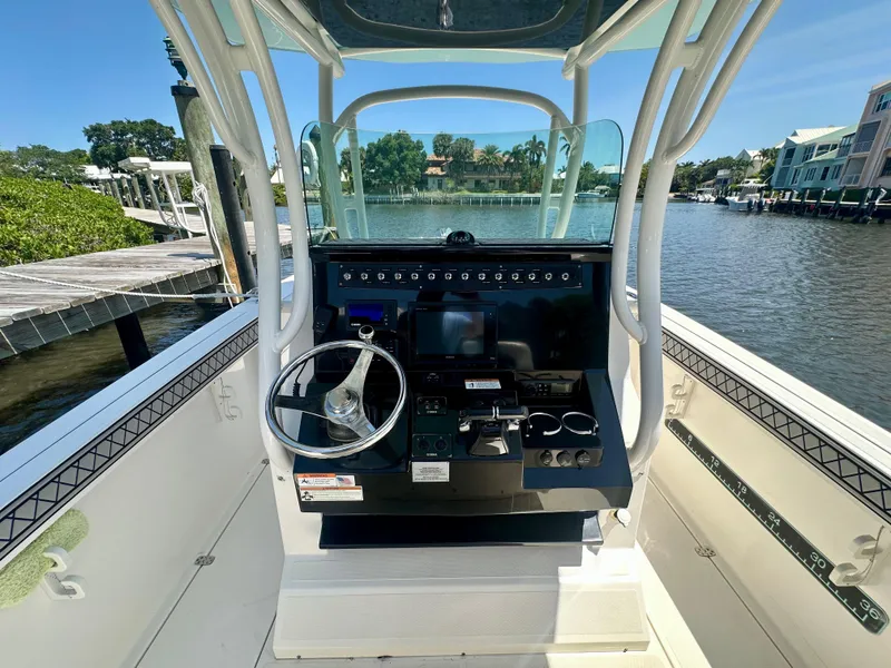 Slide: The Image of 2019 Wellcraft 262 Fisherman boat console with steering wheel, docked by a scenic waterfront. - 6