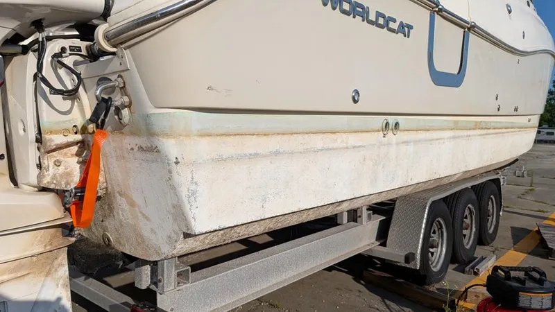 Slide: The Image of 2016 World Cat 320 DC boat on trailer, showing hull and triple-axle setup. - 13