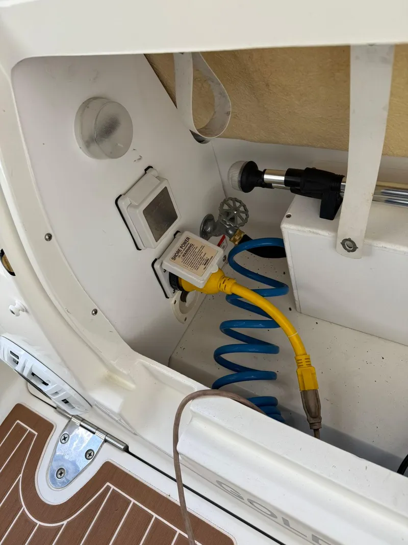 Slide: The Image of 2009 Sea Ray 250 Sundancer boat interior with utility connections and coiled hose. - 7
