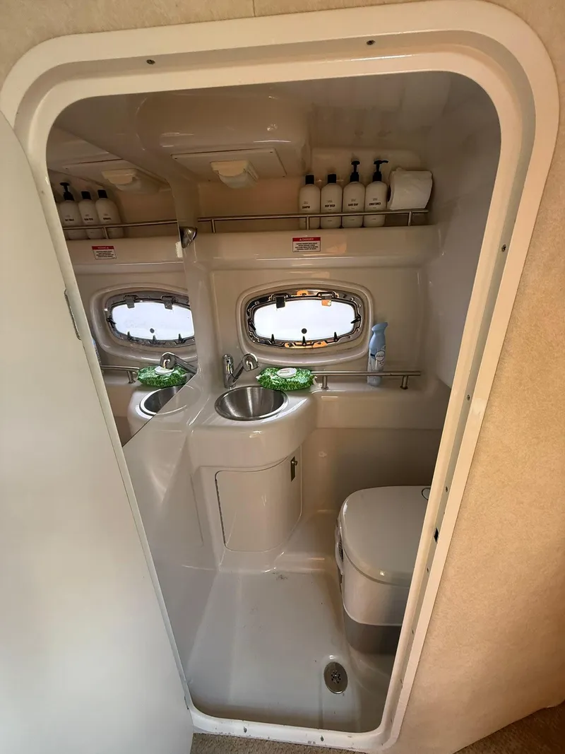 Slide: The Image of 2009 Sea Ray 250 Sundancer bathroom with sink, toilet, and porthole windows. - 8