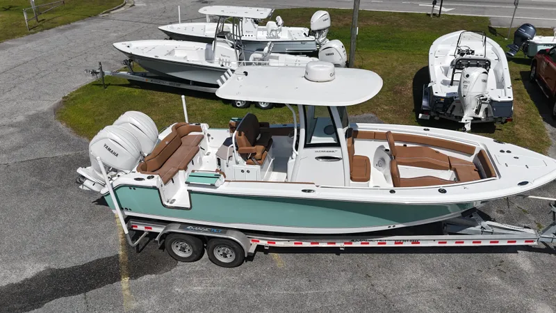 Slide: The Image of 2024 Sea Hunt Ultra 265 SE boat on trailer, parked outdoors, showcasing sleek design and dual engines. - 10