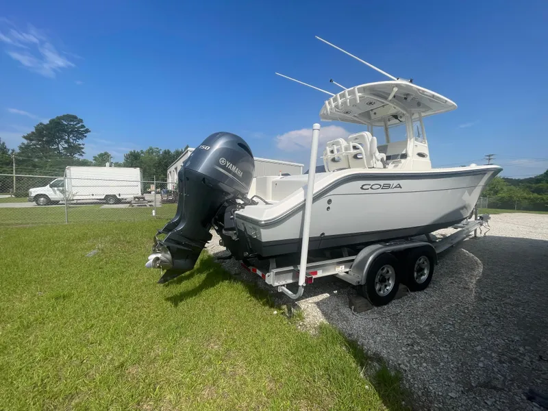 Slide: The Image of 2020 Cobia 262 Center Console boat on trailer, parked on grass under clear blue sky. - 5