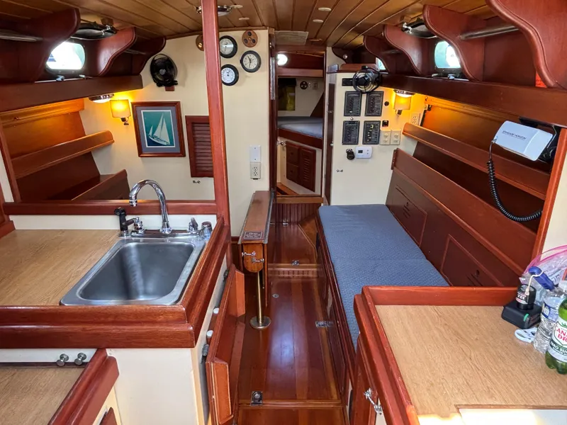 Slide: The Image of Interior of 1955 Hinckley 36 Auxiliary Yawl, featuring wood finishes and compact kitchen area. - 31