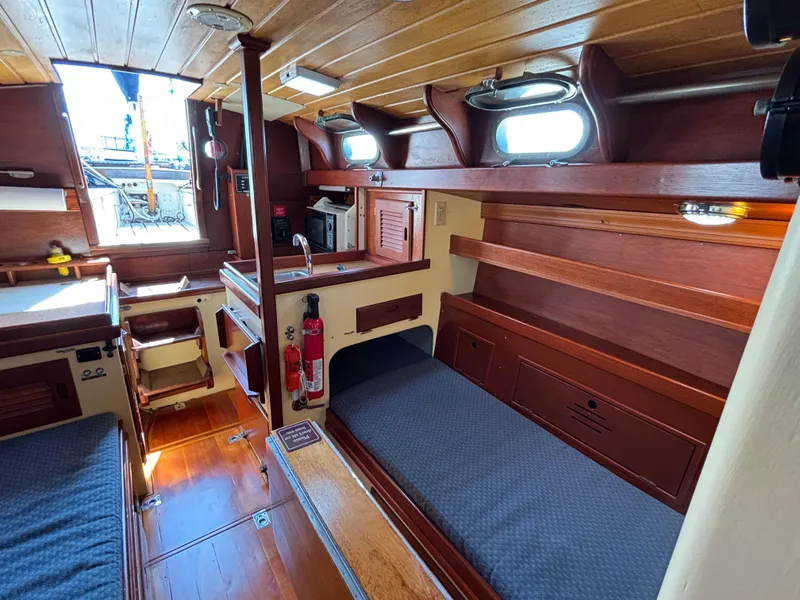 Slide: The Image of 1955 Hinckley 36 Auxiliary Yawl interior with wooden finish and cozy sleeping area. - 37