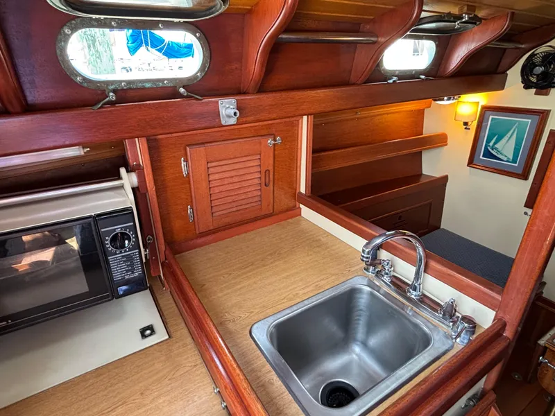 Slide: The Image of Interior of 1955 Hinckley 36 Auxiliary Yawl with sink, microwave, and wooden cabinetry. - 43