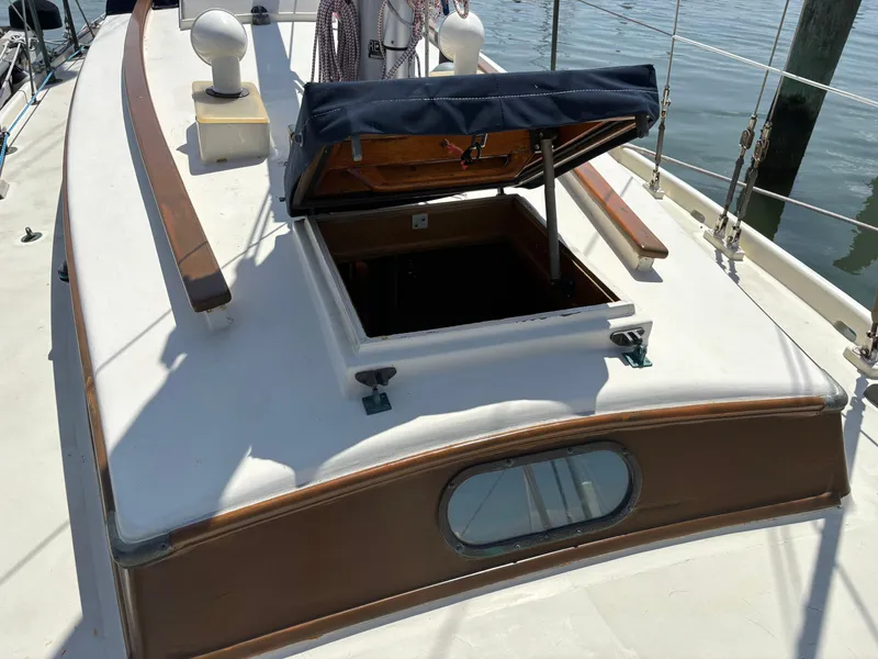 Slide: The Image of Hinckley 36 Auxiliary Yawl 1955 with open hatch on deck, docked by water. - 8