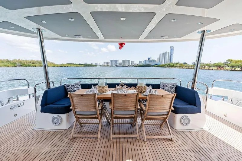 Slide: The Image of Luxurious 2019 Sunseeker 86 Yacht deck with dining area, overlooking serene waterfront cityscape. - 16