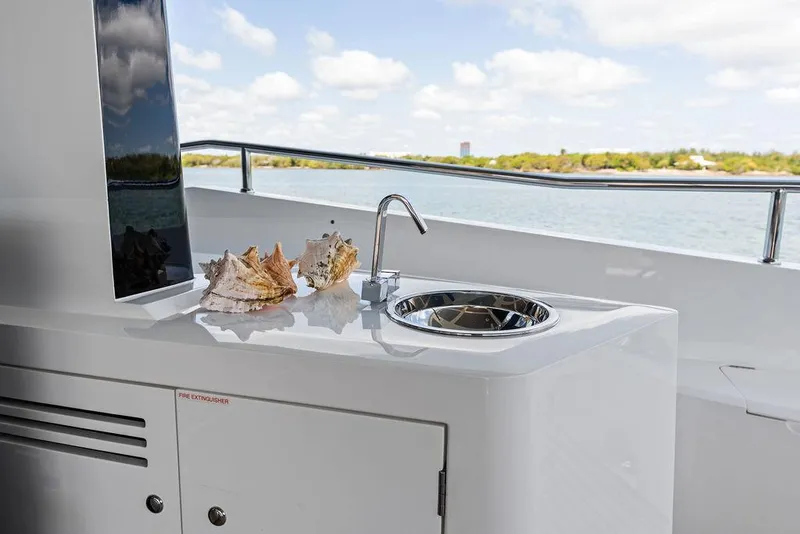 Slide: The Image of Luxury Sunseeker 86 Yacht 2019 with outdoor sink and seashells, overlooking serene waters. - 19